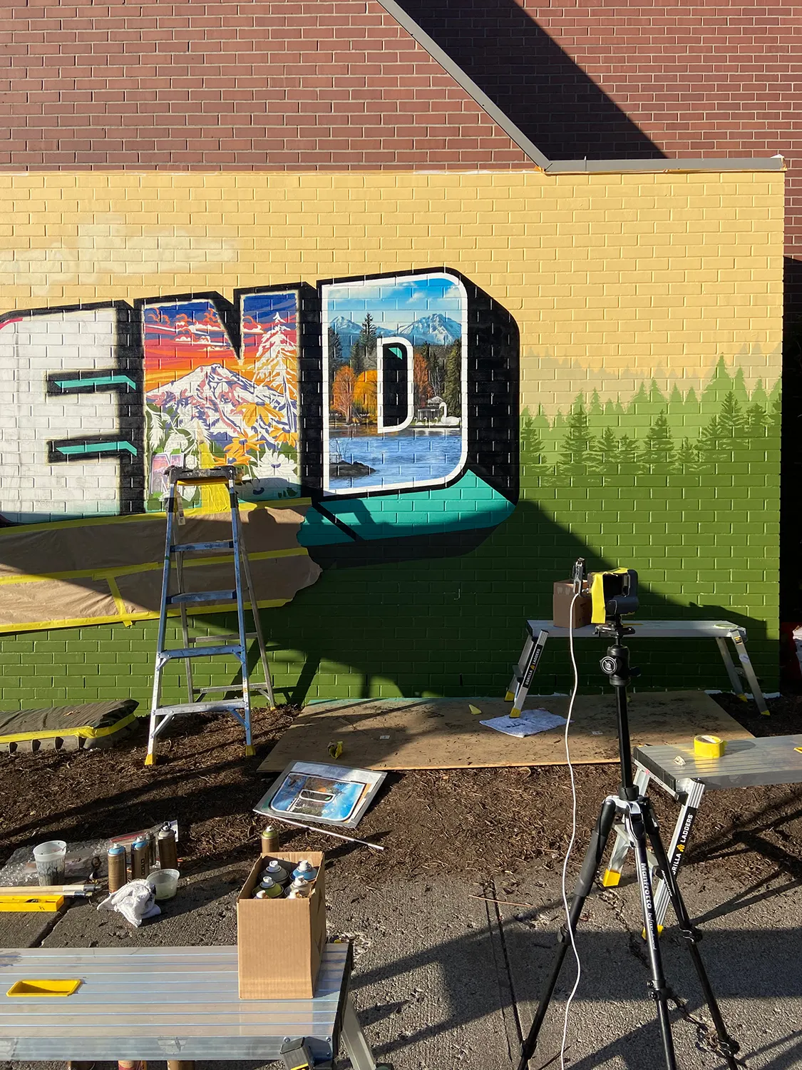 Artists working from ladders across the Greetings from Bend lettering