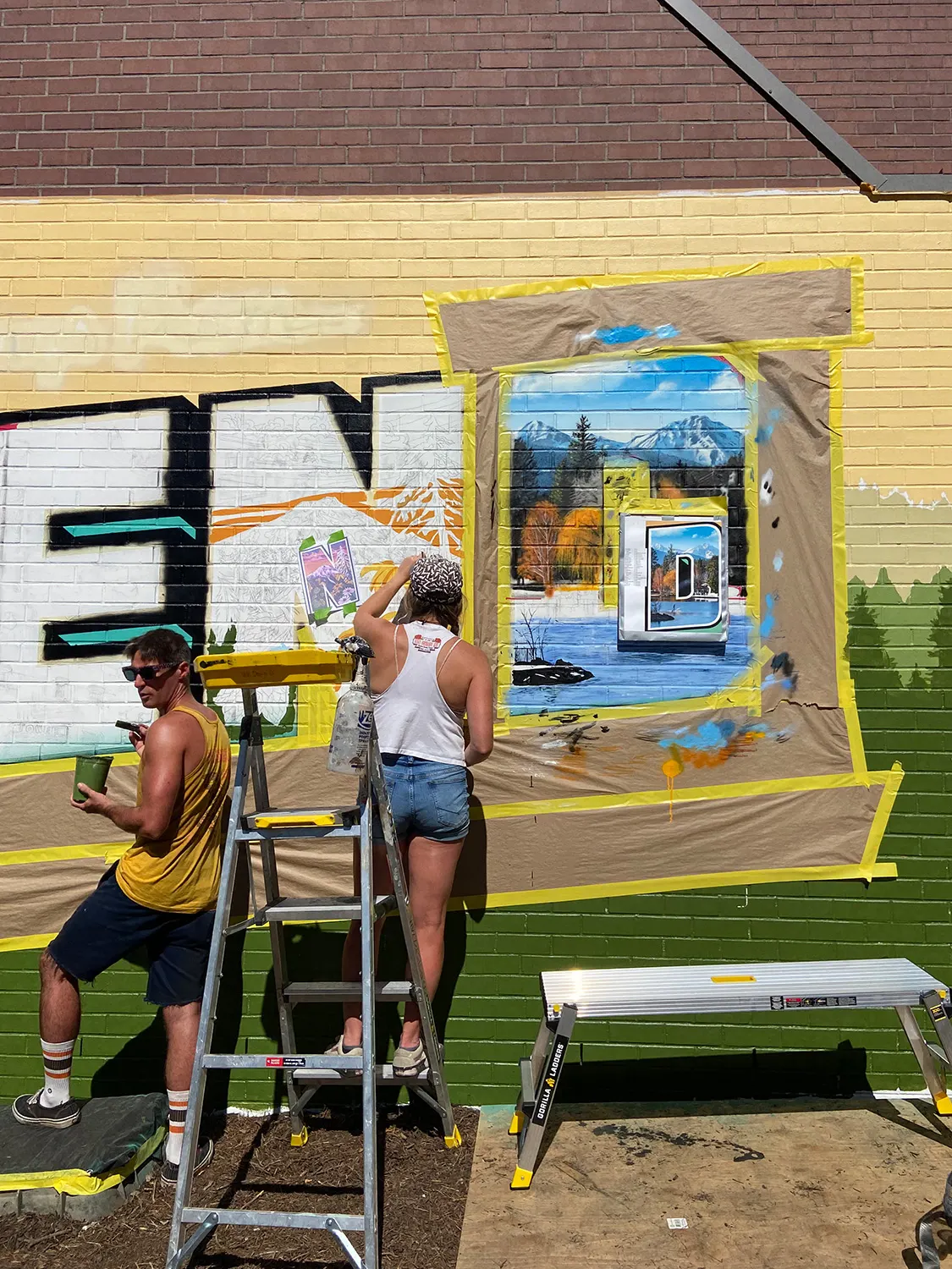 Two artists painting landscape details inside the N and D letters