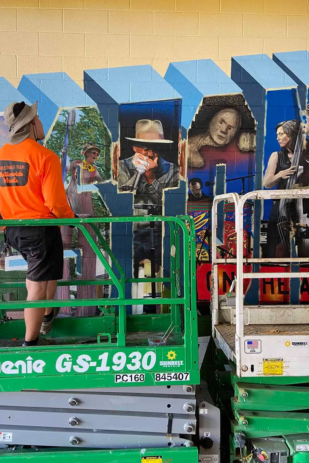 Artists working from lifts on portraits and landmarks inside the letters