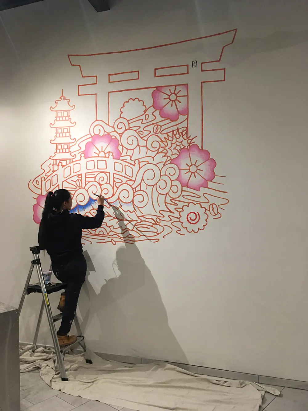 Artist painting the fine red outlines of the Futago Udon mural