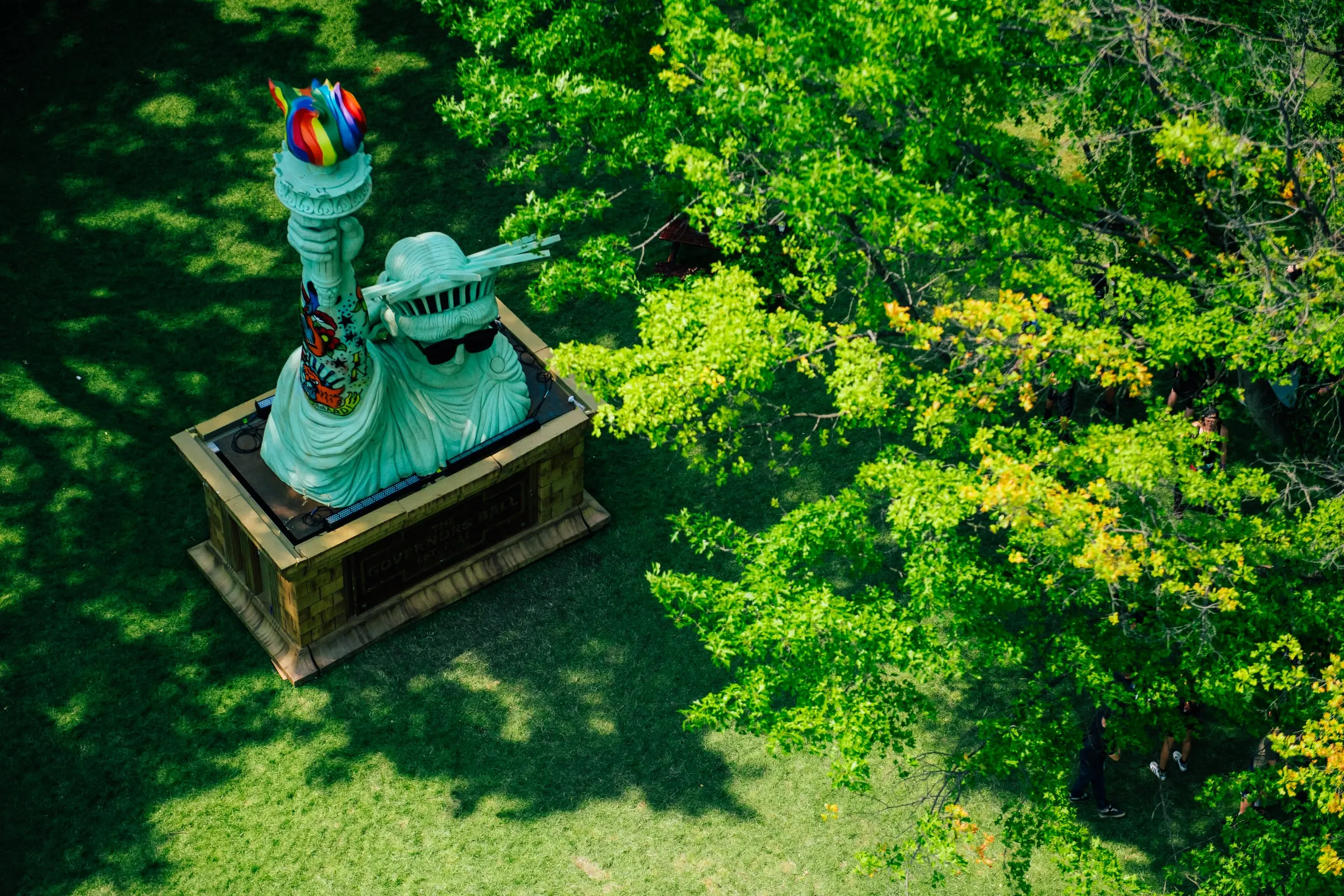 Aerial view of the GovBall Statue of Liberty in Randall's Island Park with a rainbow-painted torch and tattoo sleeve