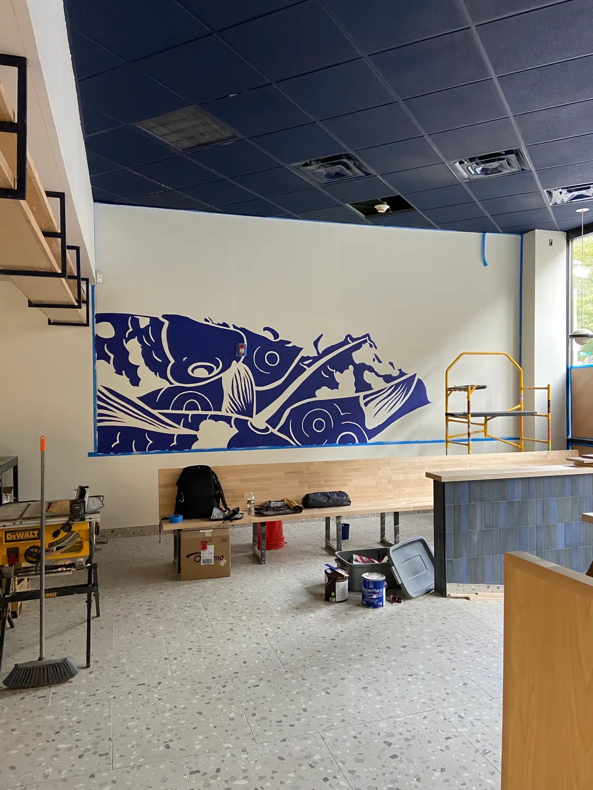 Early painting stage with deep blue koi forms blocked onto the restaurant wall
