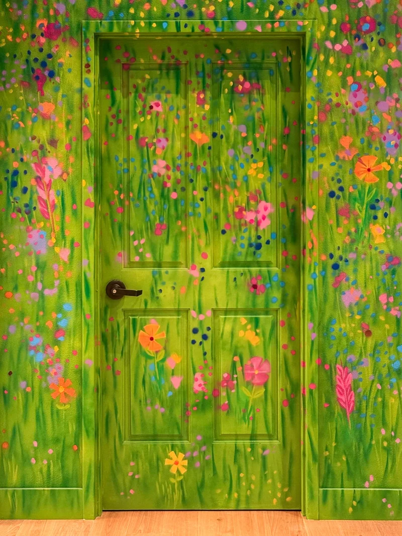 Close view of the green playroom door painted with tall grass and bright wildflowers