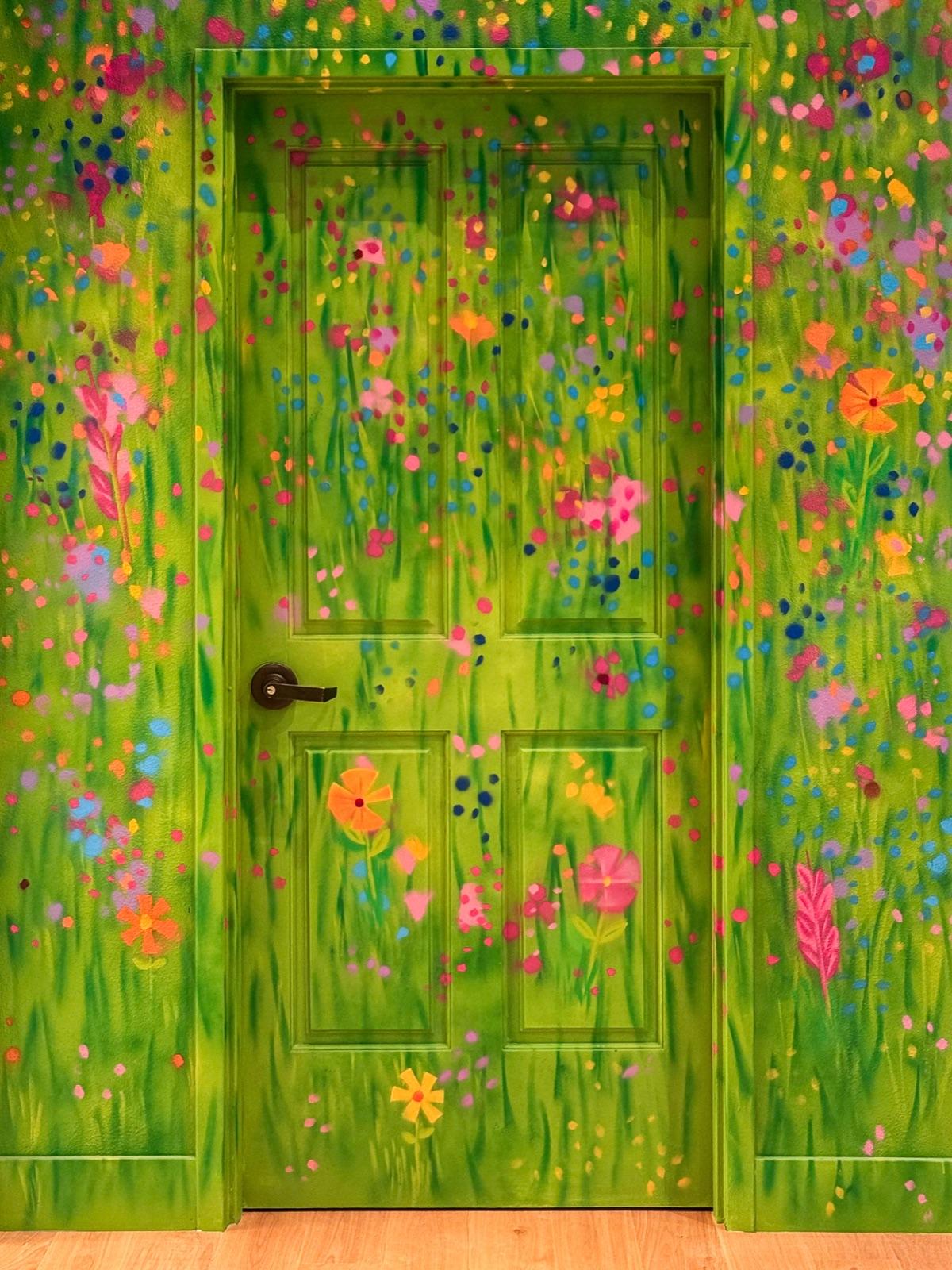 Close view of the green playroom door painted with tall grass and bright wildflowers