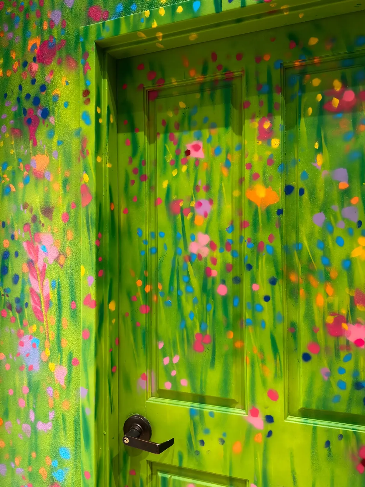 Angled detail of the green painted door and the surrounding wildflower mural