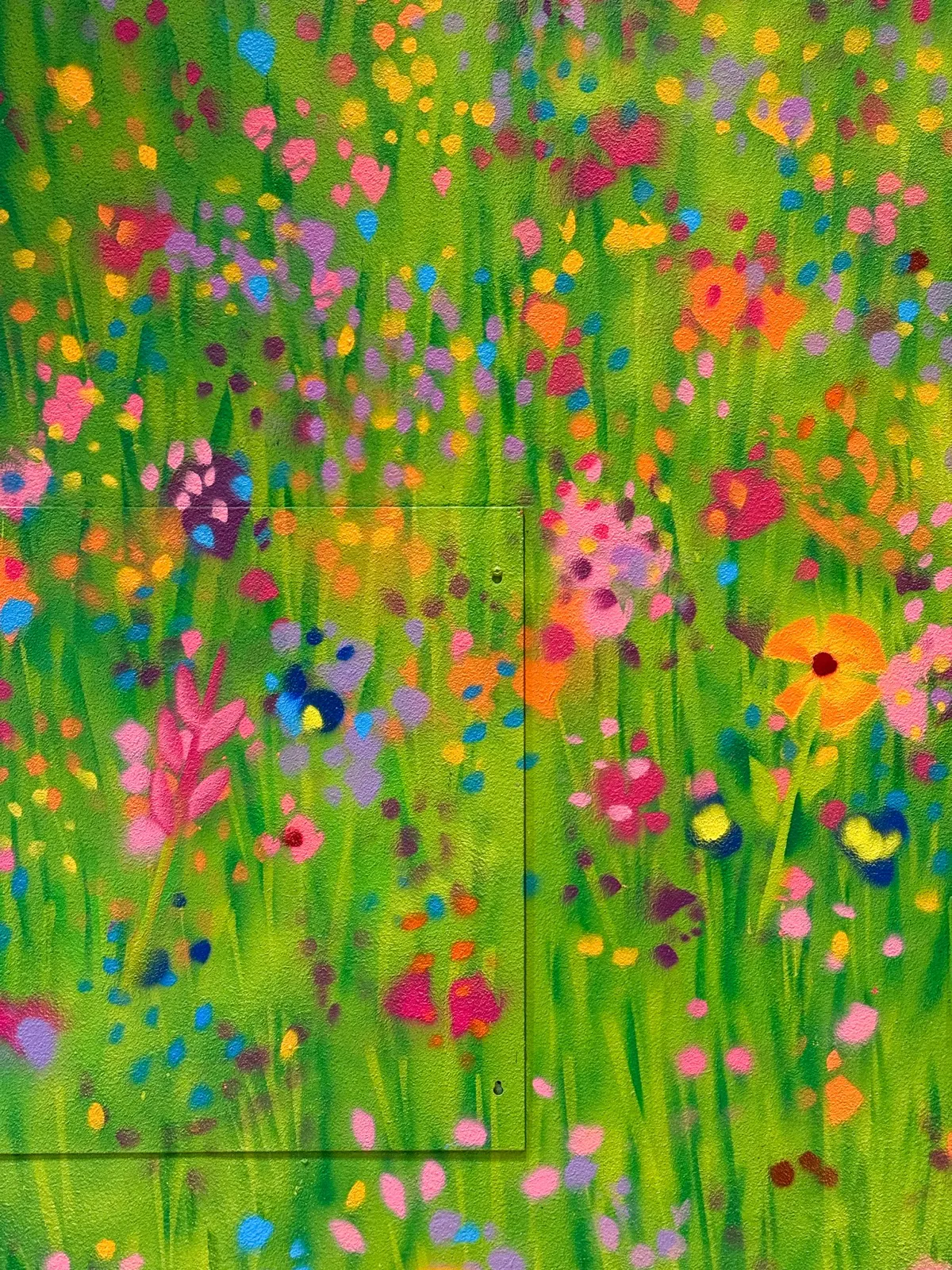 Close view of layered meadow flowers and painted marks continuing across a wall access panel