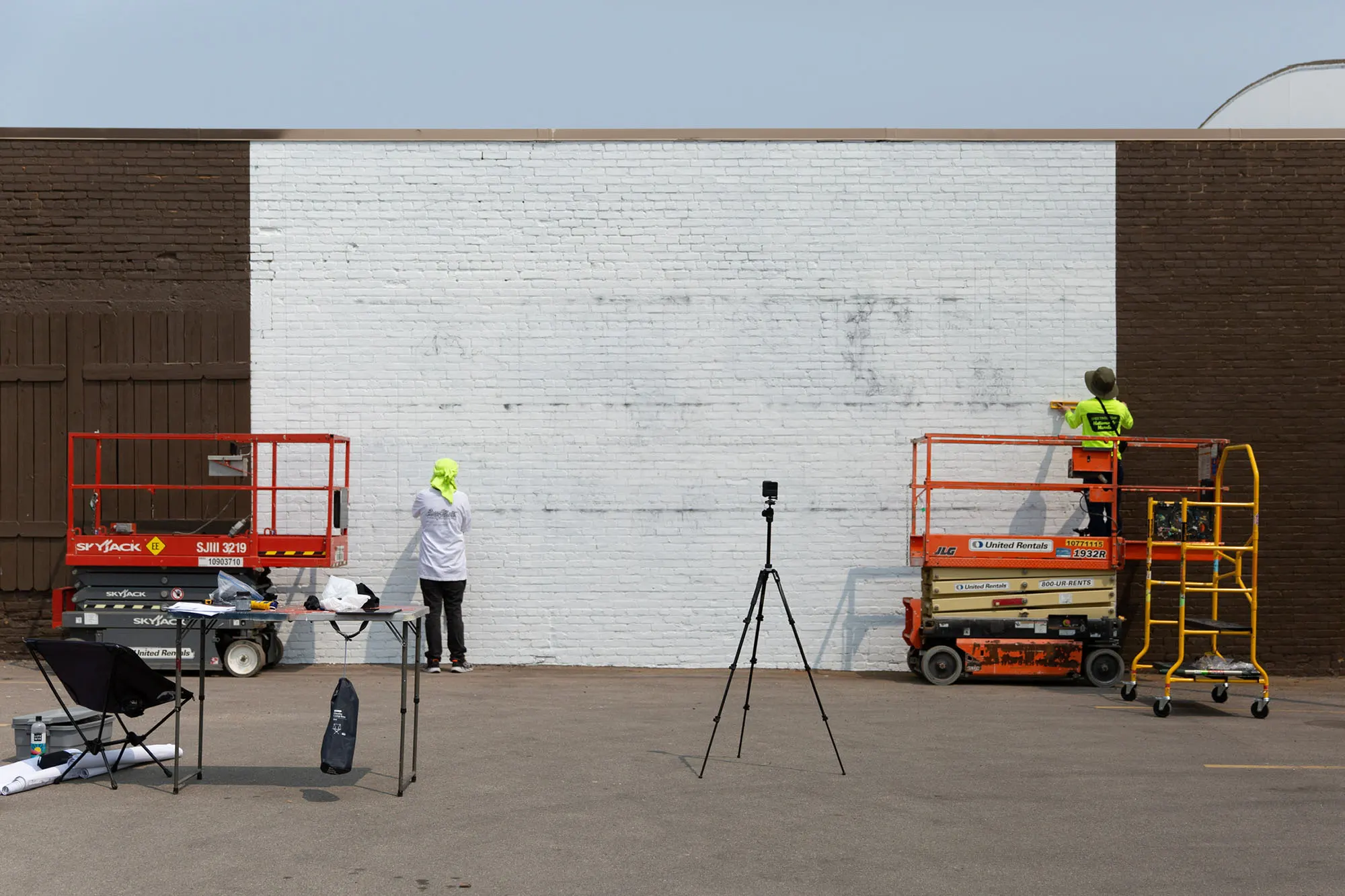 Artists and lifts at the primed Oshkosh wall before painting began