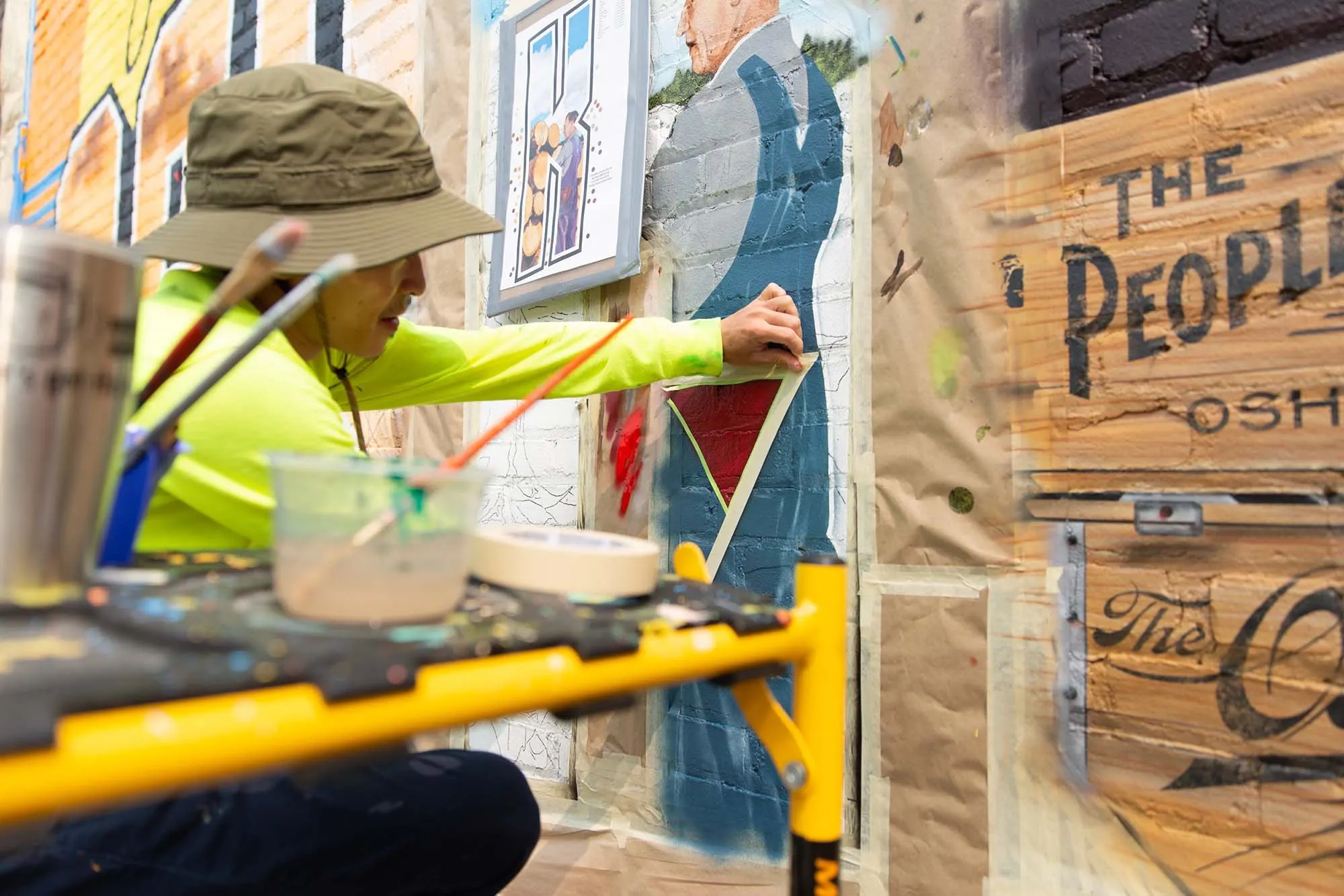 Artist brush-painting the lumber history scene inside the letter K