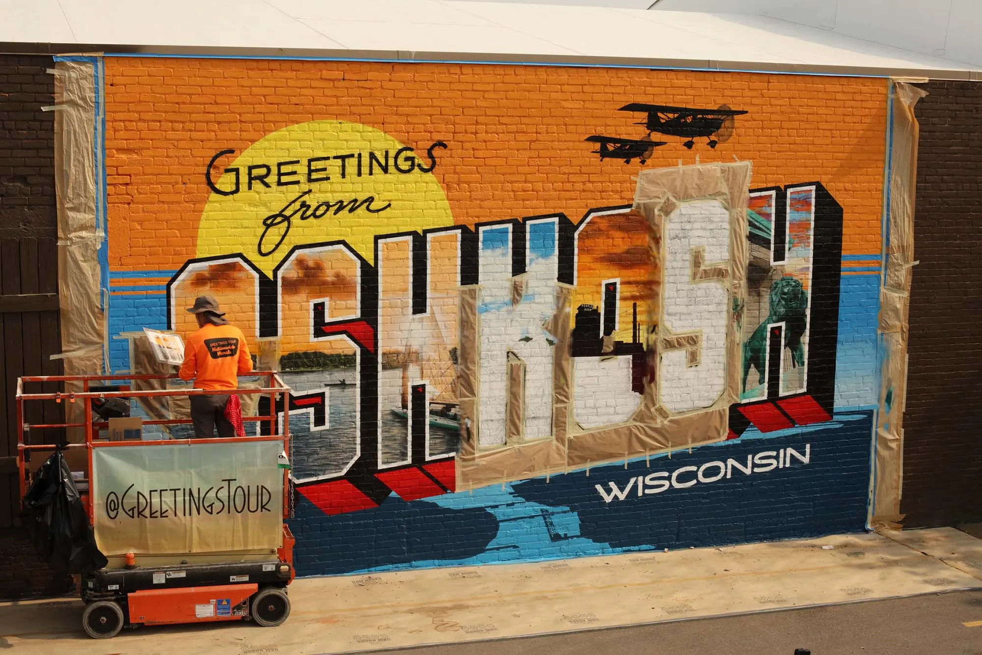 Greetings from Oshkosh mural midway through painting and masking