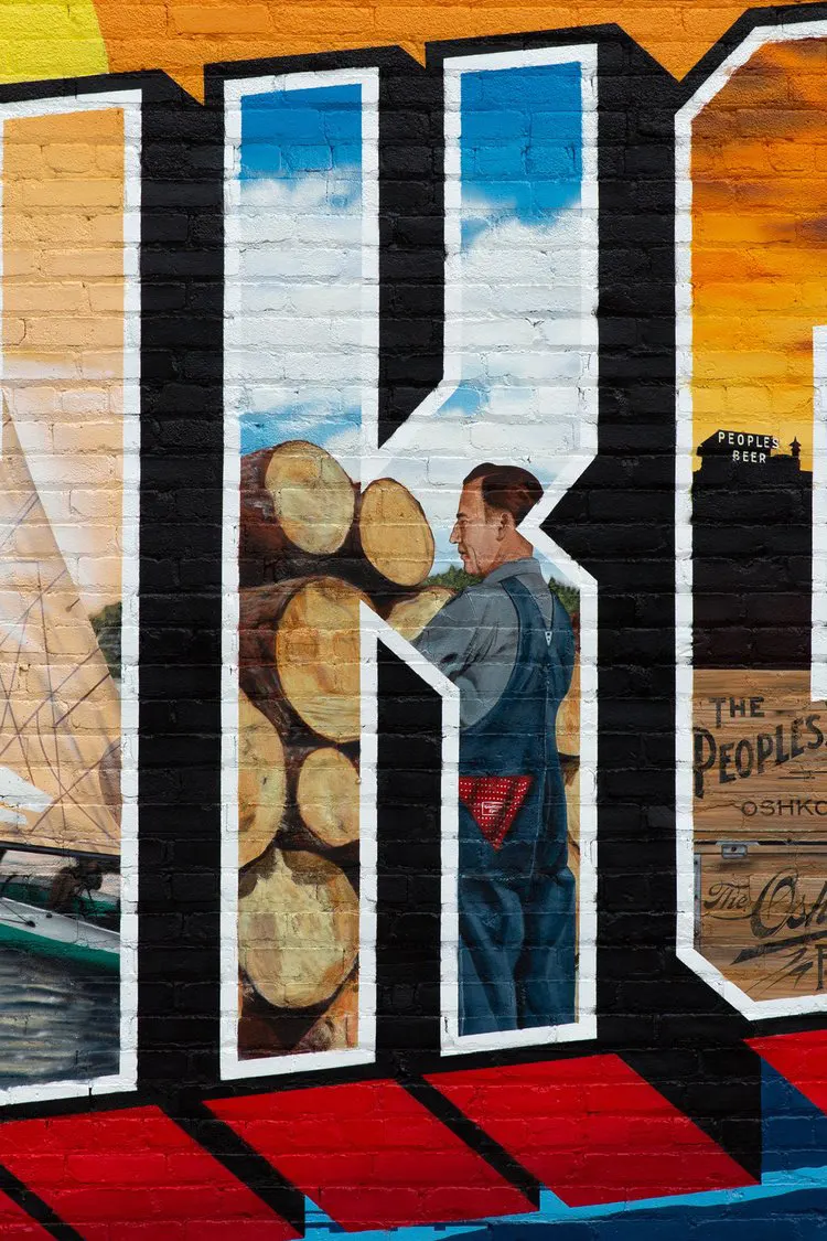 Logs and a lumber worker painted inside the letter K
