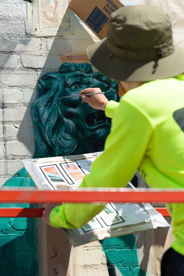 Artist painting fine details on the Oshkosh library lion