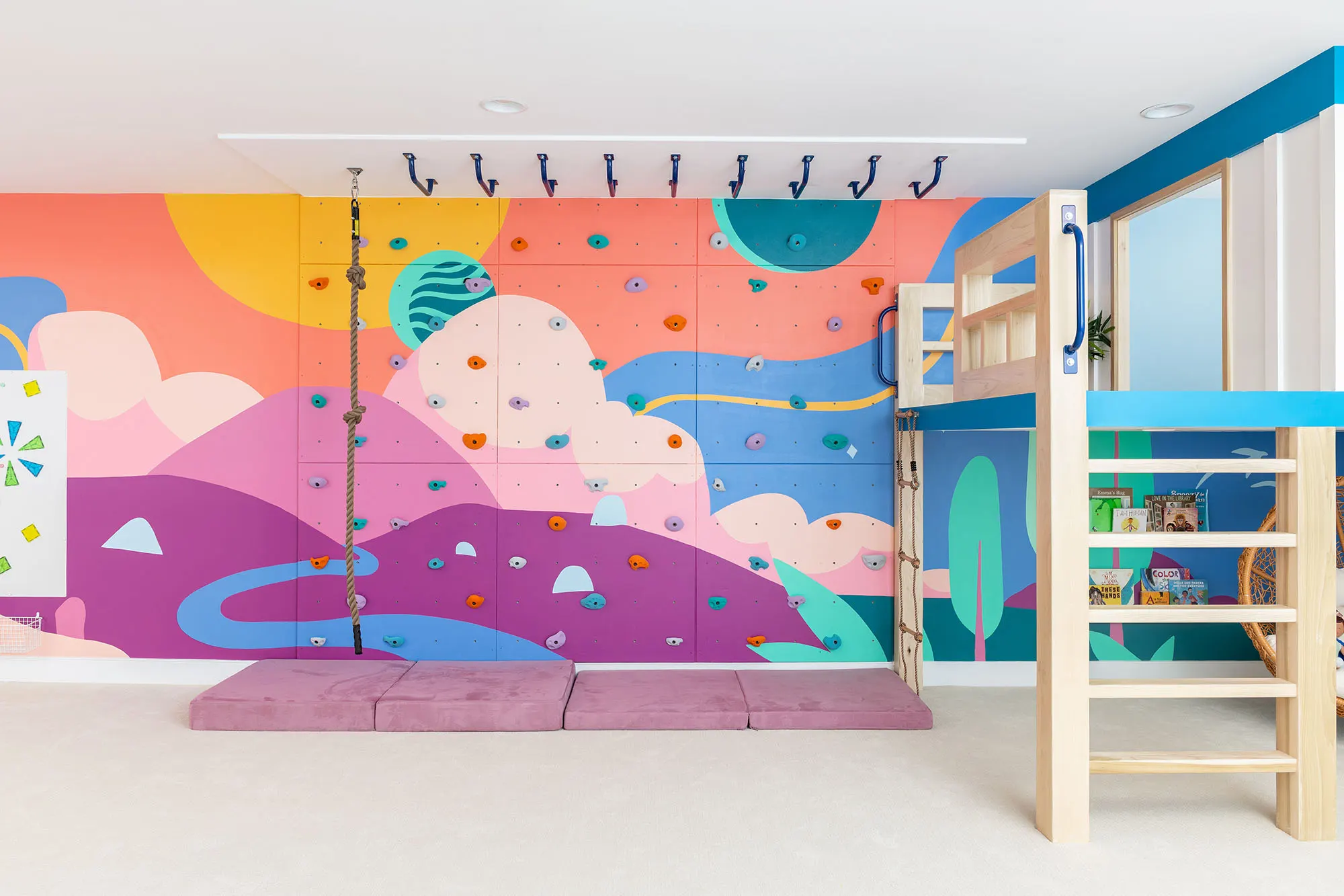 Pink and orange landscape mural behind the playroom swings