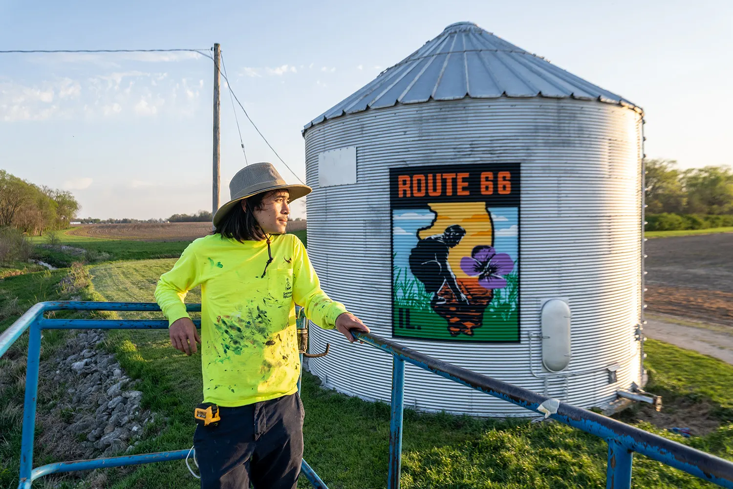 American Mural painter standing in front of the finished silo