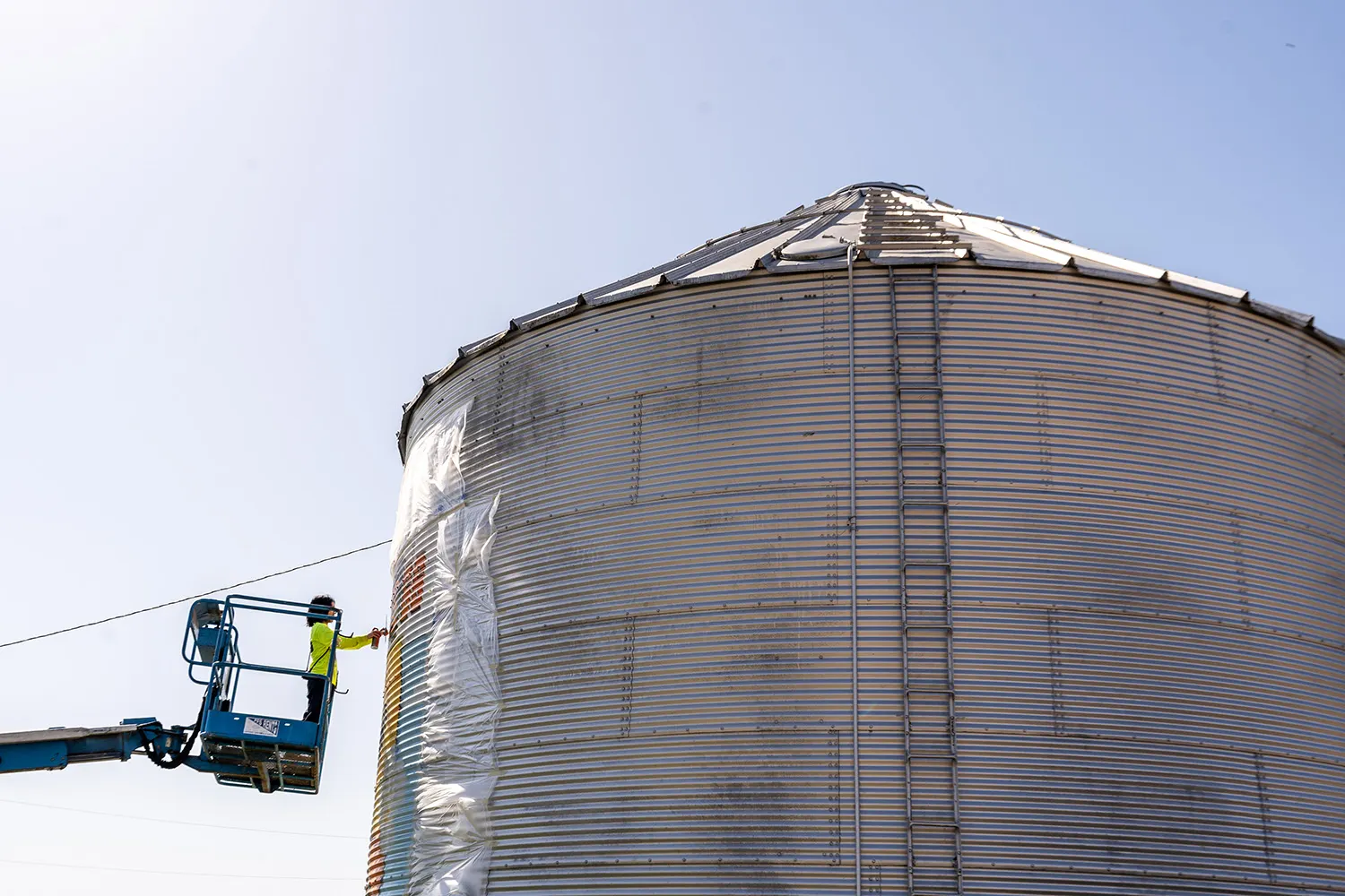 Painter working from a lift on the corrugated metal silo
