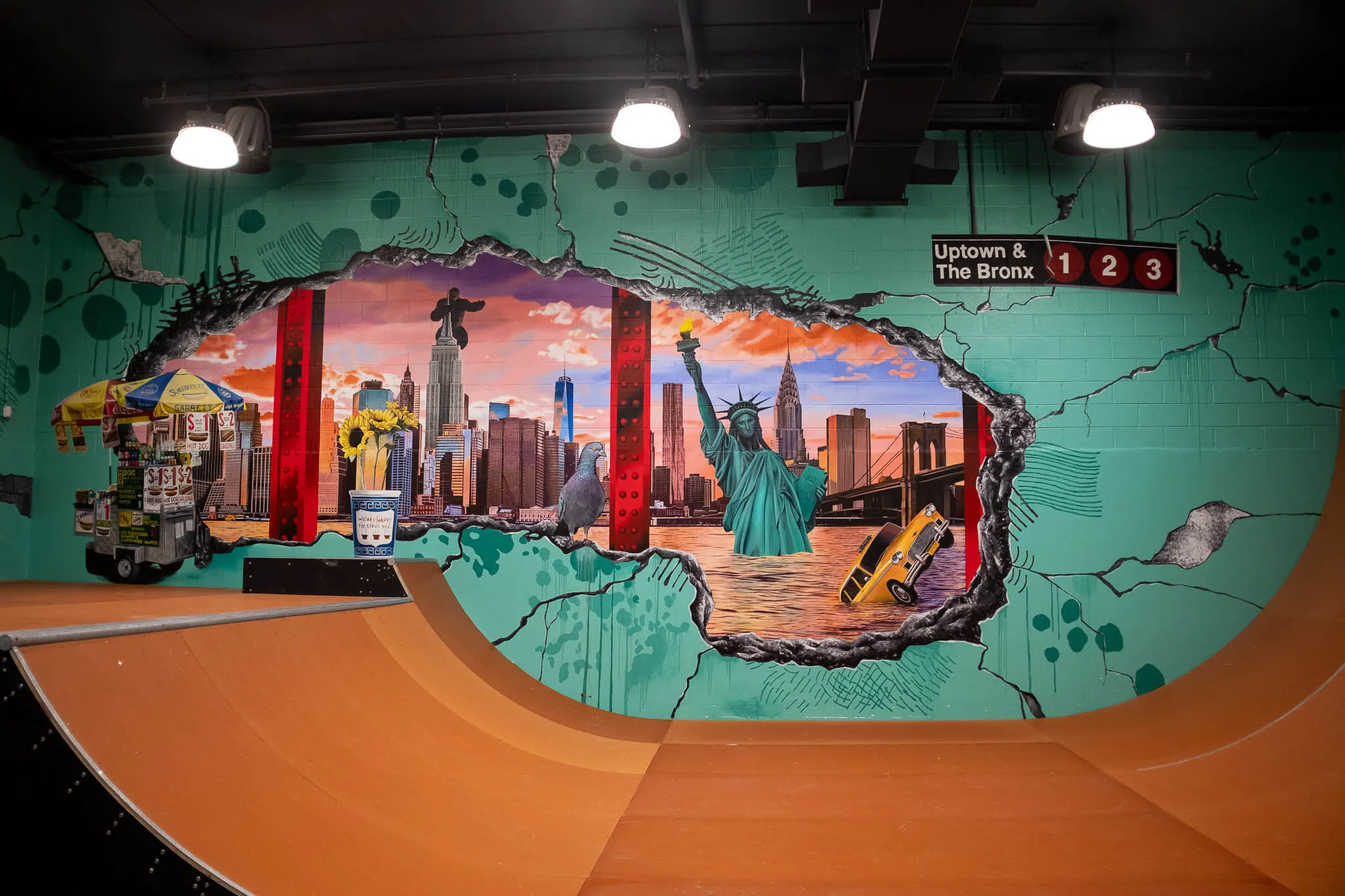 Sunset skyline and Statue of Liberty mural above an orange skate ramp