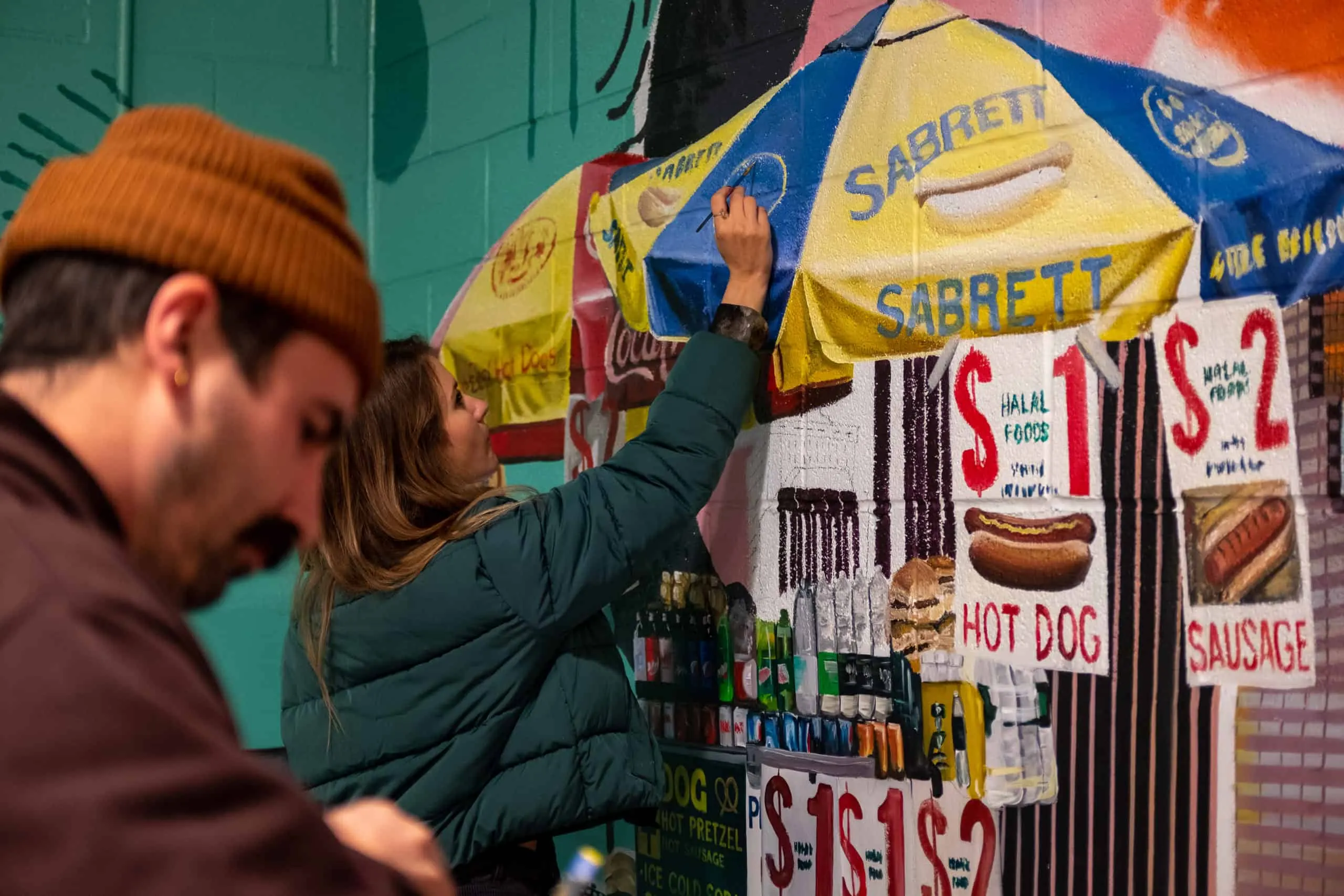 Artists painting the small signs and canopy on a Sabrett hot dog cart