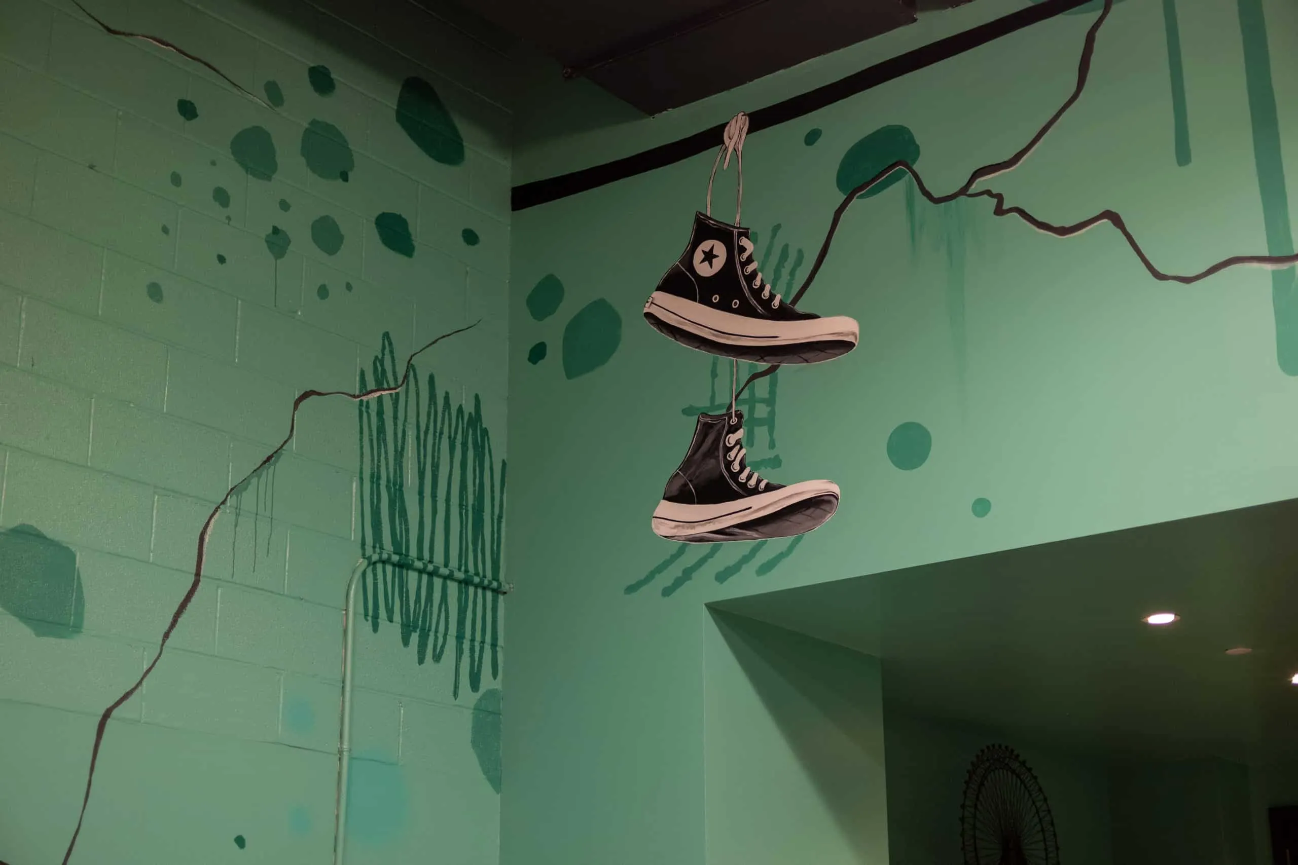 Pair of painted Converse sneakers hanging from a wire