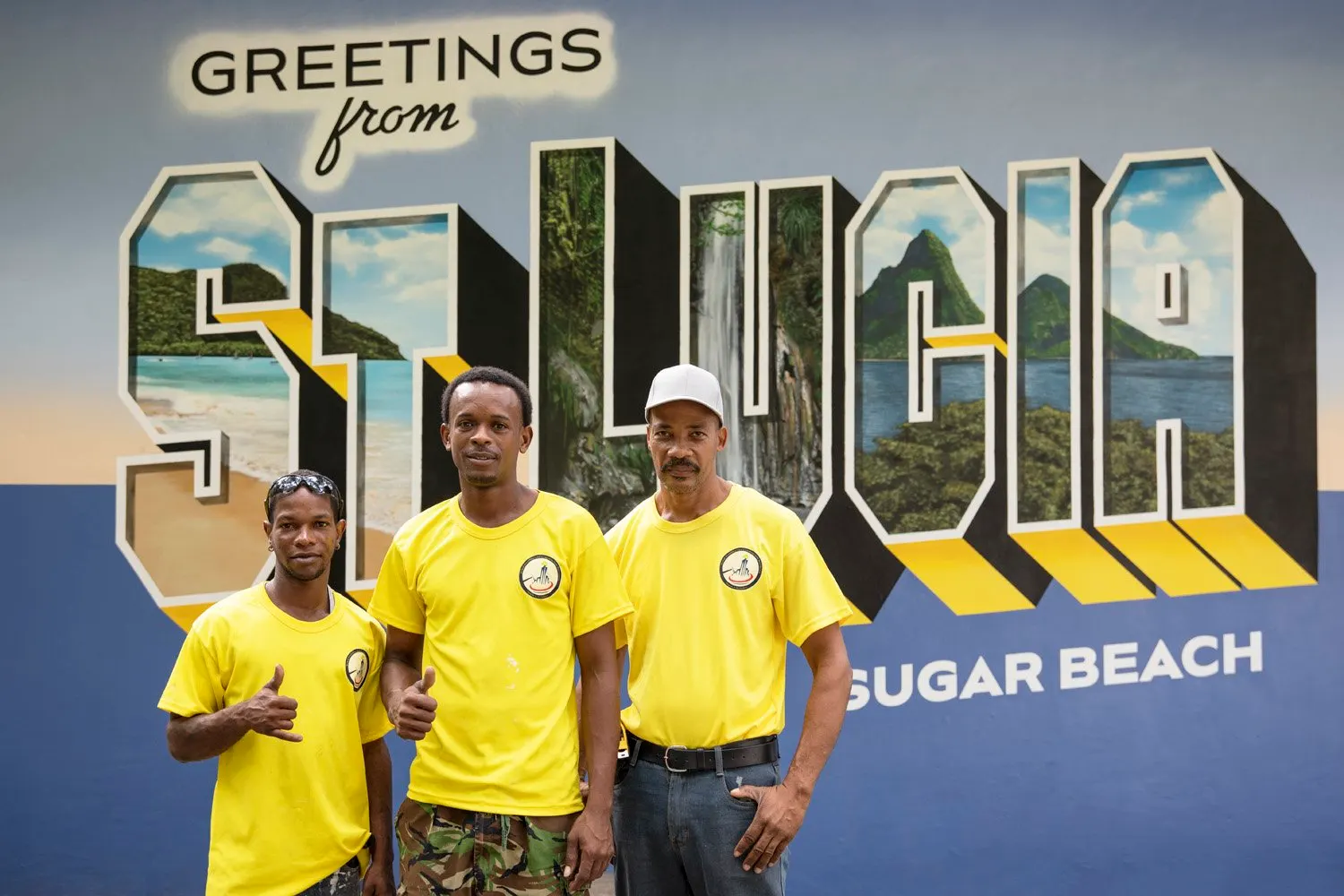 Three members of the mural production team in front of the finished lettering