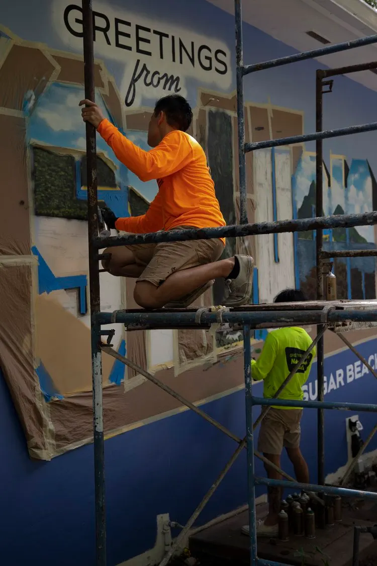 Artists painting the St. Lucia postcard letters from scaffolding