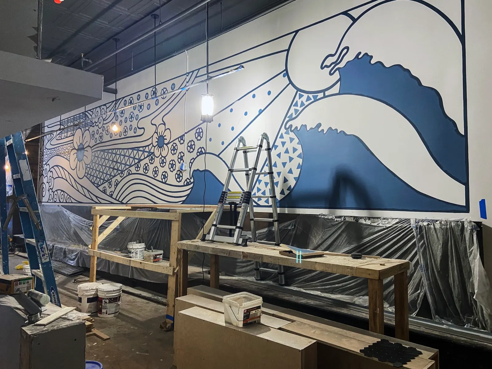 Wide view of the Sugidama dining-room mural during painting with platforms and ladders