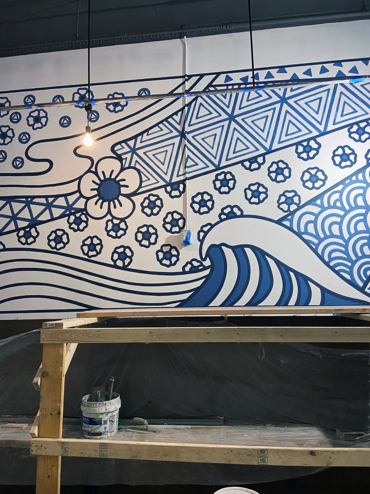 Indigo mural detail with a breaking wave, blossoms, and geometric tile patterns