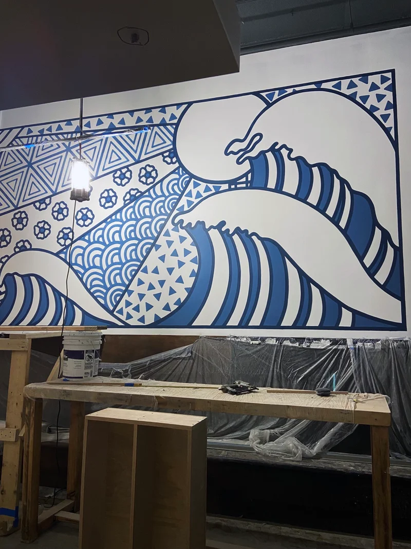 Large striped waves and a sun against indigo geometric patterns on the Sugidama dining-room mural