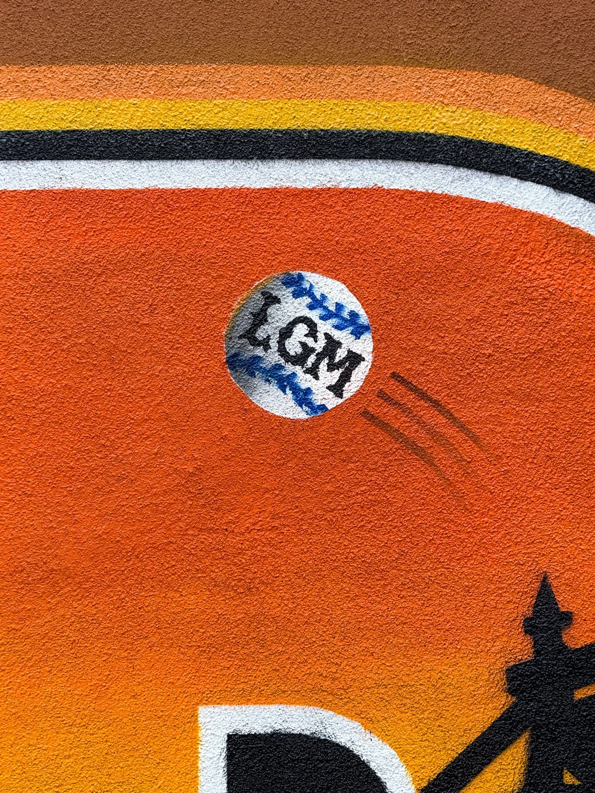 Close view of a painted baseball above the Queensboro Bridge inside the Sunnyside mural lettering