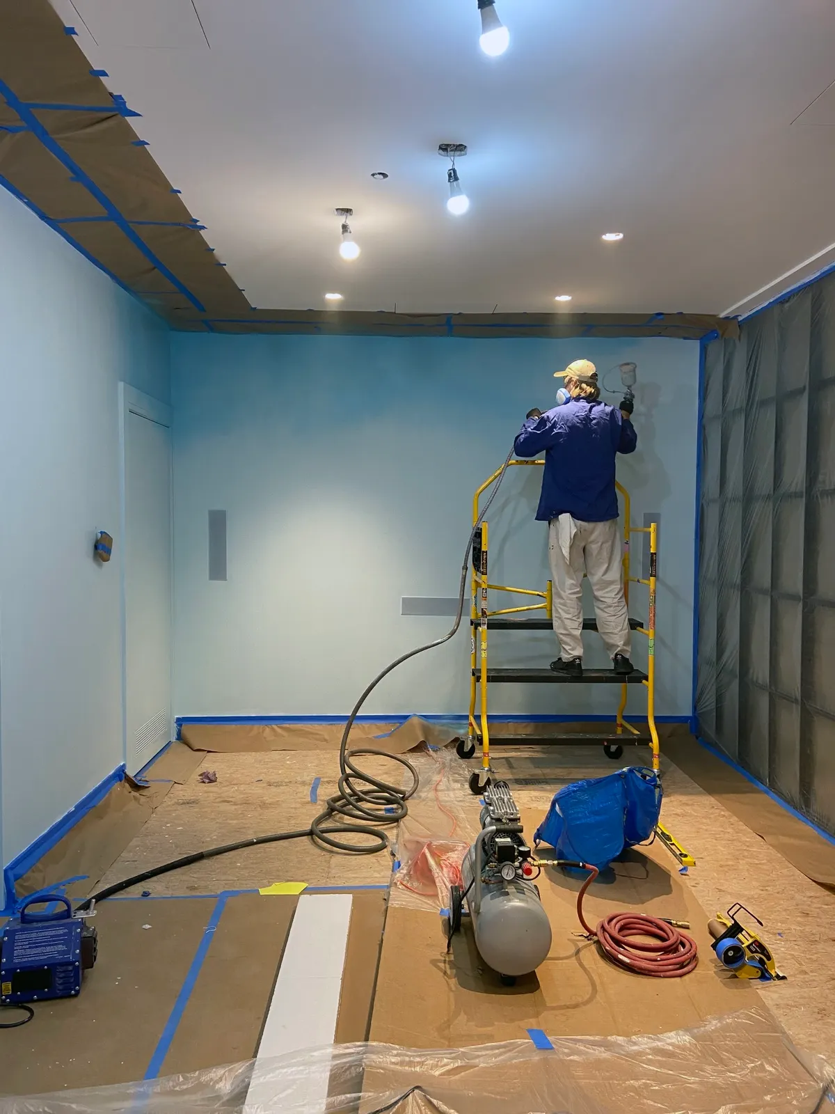 Painter using an HVLP spray gun on the blue base of the Tribeca cloud mural