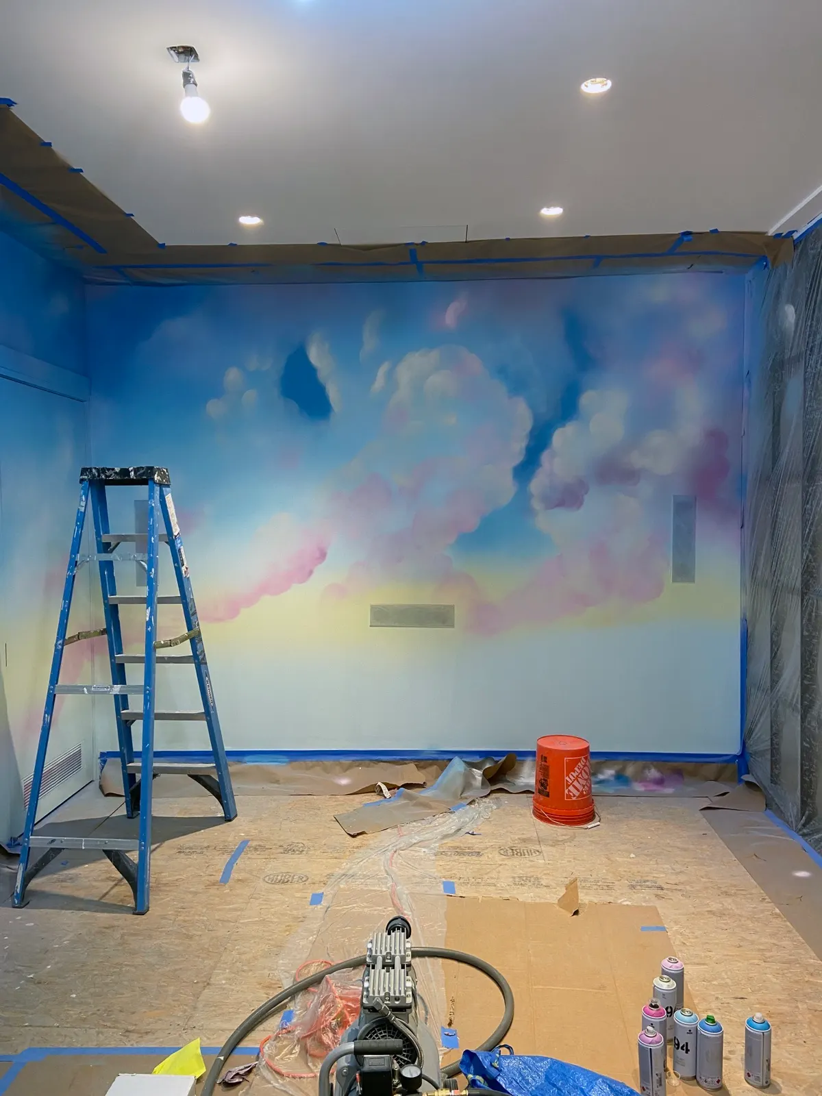 Large white clouds airbrushed over a blue and pink sky during the Tribeca mural installation
