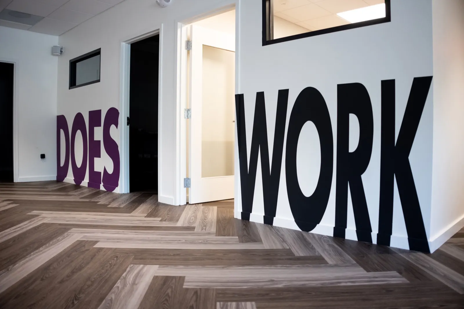 Purple Does and black Work lettering completing the phrase across the office hallway