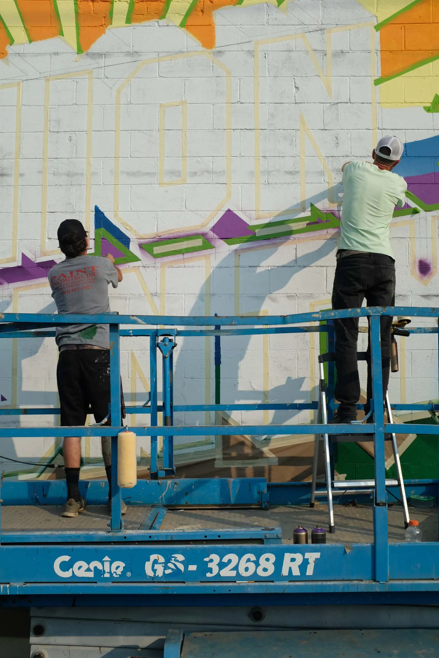Two artists building the letter shapes and mountain background from lifts