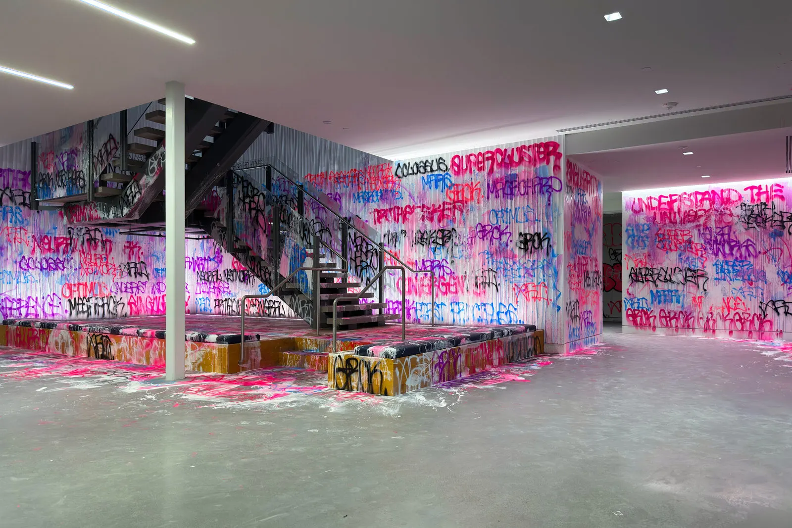 Wide view of fluorescent graffiti covering the walls and floor around the xAI office entrance