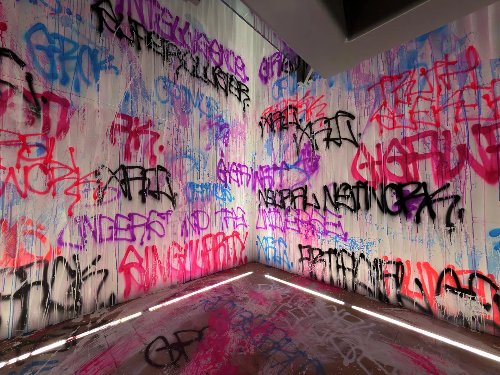 Close view of overlapping pink, blue, and black graffiti in an office corner