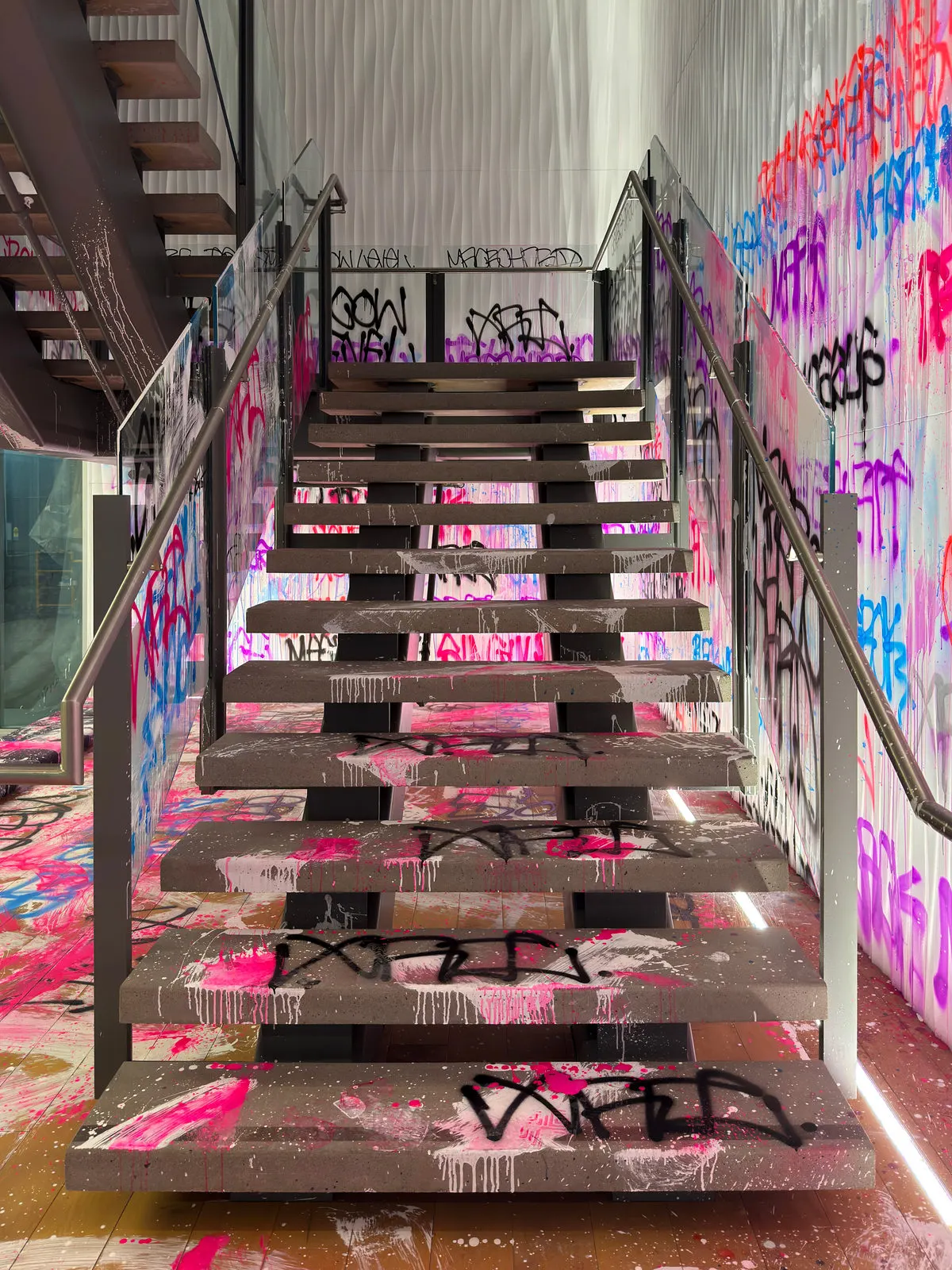 Stairway covered with fluorescent tags leading through the painted xAI entrance