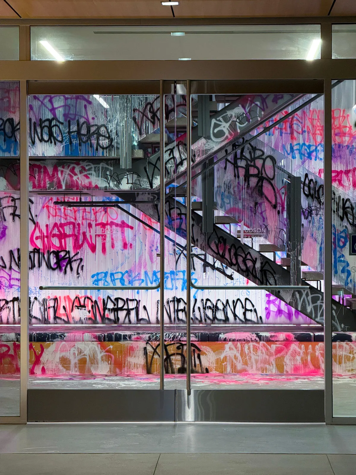 Portrait view through glass of the tagged walls, staircase, and platform