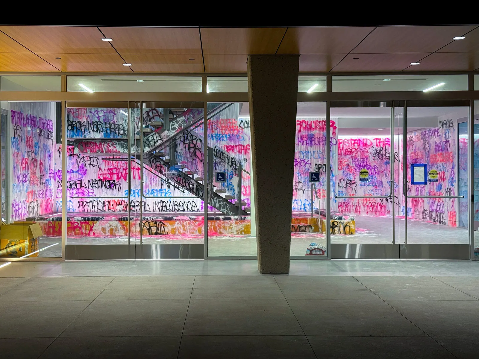 Wide exterior view through glass of the fluorescent xAI graffiti installation